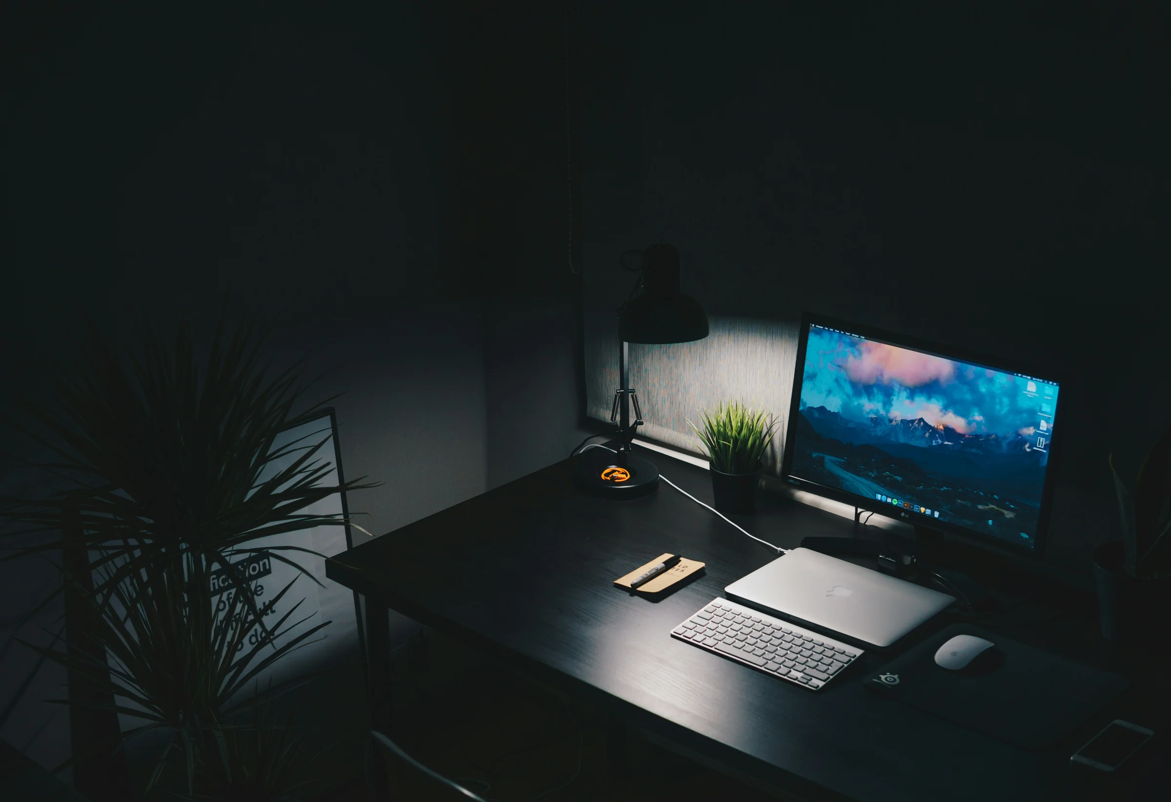 A keyboard and monitor on a dark desk.